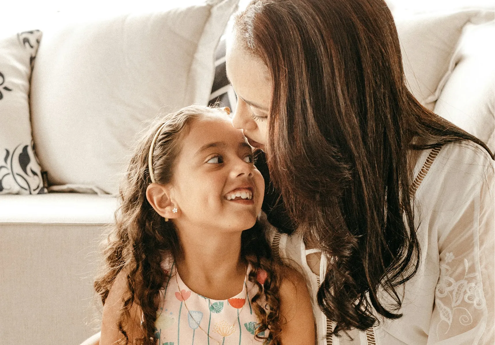 A mother and daughter sharing a laugh on the couch at home