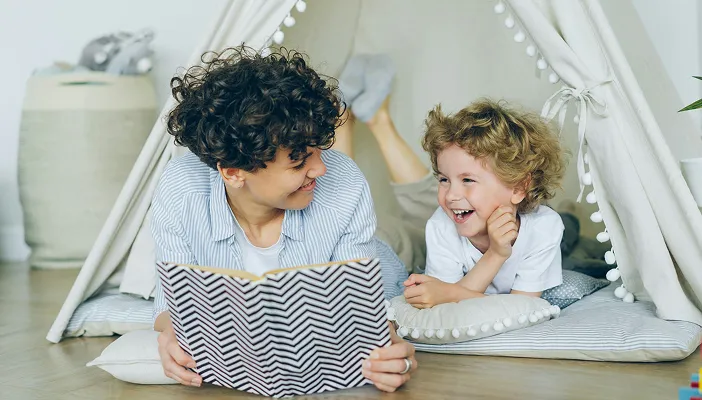 Reading a book together inside a blanket teepee